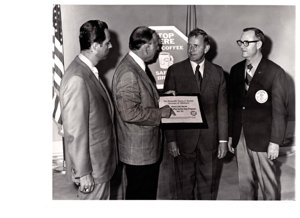 ["The image depicts Dewey Bartlett standing with Jerry Cord Wilson, Jack Durland and Jack Ward in a ceremony for Bartlett to accept the honorary chairmanship of the National Coffee Safety Stop Program"]