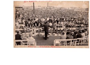 ["The image depicts Dewey Bartlett seated with many others, behind Richard Nixon who is speaking to a large Oklahoma crowd"]
