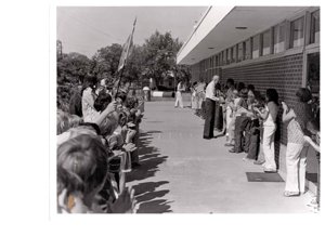 ["The image depicts Dewey Bartlett shaking hands with many school children at the Medford Public School"]