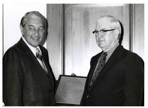 ["Black and white photograph of Tom Steed with Rex Davis, director of the Bureau of Alcohol, Tobacco and Firearms standing with an award."]